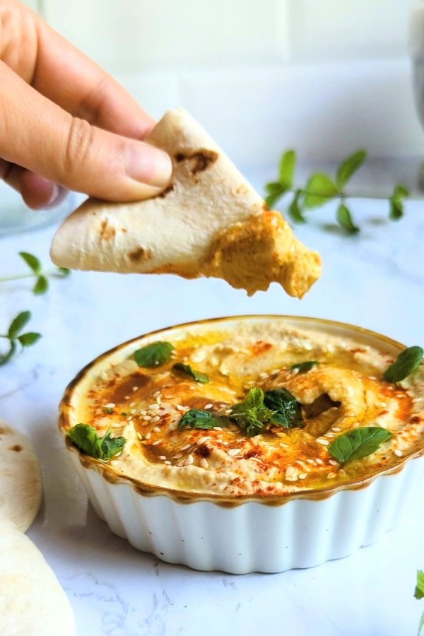 salt free hummus with pita bread dipping into the hummus topped with olive oil mint or fresh herbs and smoked paprika hummus for a great no sodium snack.