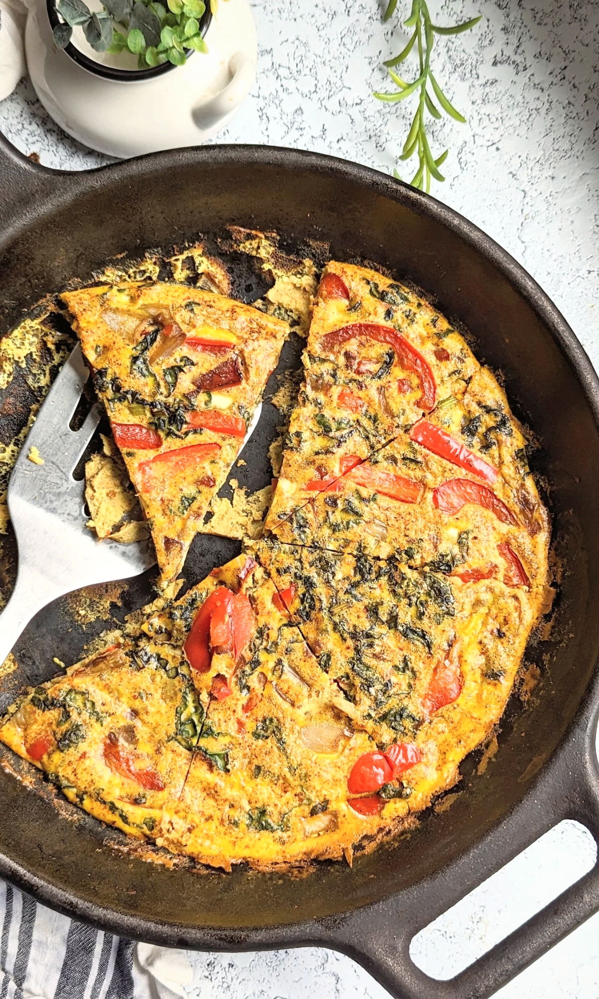 Mediterranean egg recipe in a cast iron skillet with red bell pepper kale caramelized onions and red chili pepper flakes, a no salt breakfast idea.