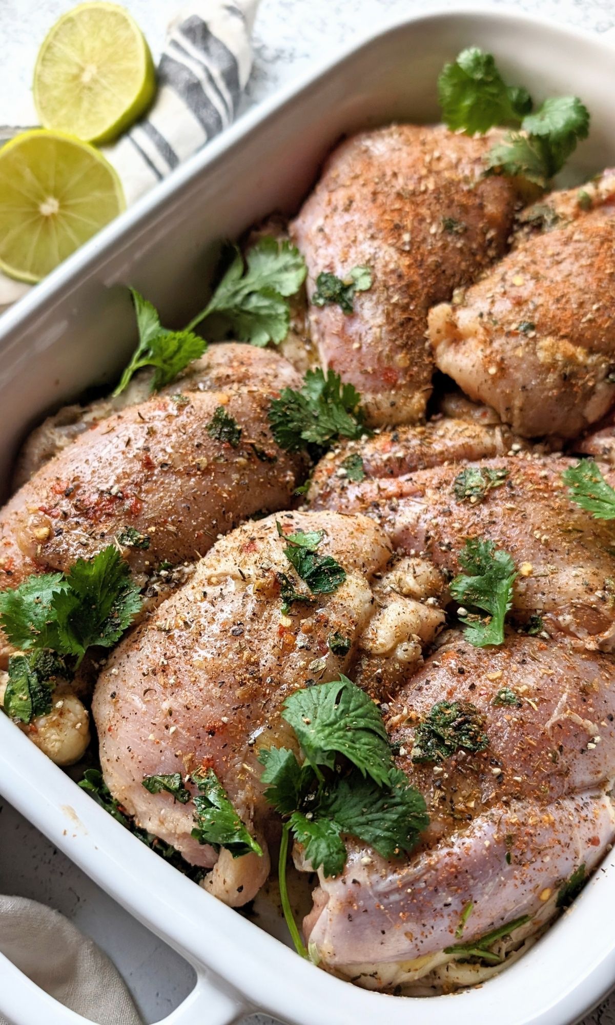 low sodium jerk marinade recipe with allspice cinnamon and ginger over chicken thighs in a baking dish with fresh herbs and lime