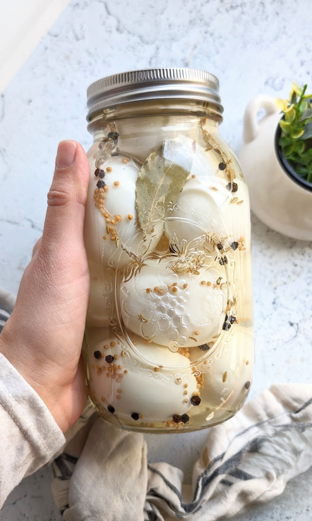 a jar of salt free pickled eggs with red chili pepper flakes peppercorns and bay leaves
