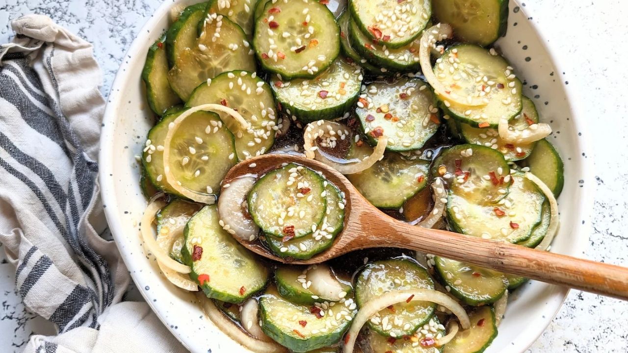 cucumber salad with rice vinegar dressing and sliced onions in a bowl with a wooden spoon picking up this low sodium asian recipe