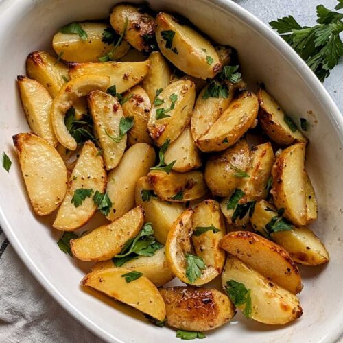 low sodium greek potatoes with lemon and parsley roasted in the oven in a casserole dish