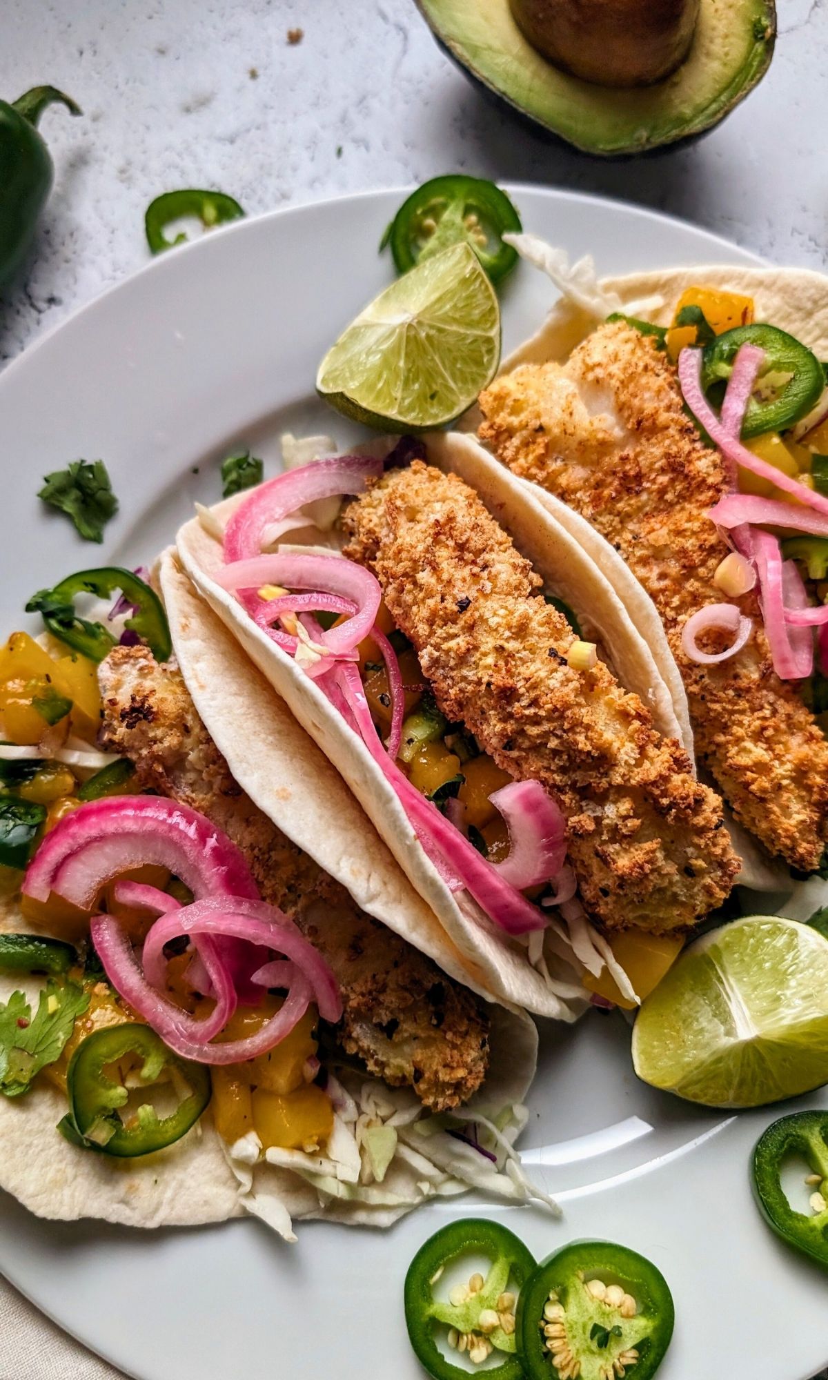 no salt added tacos with crispy white fish and low sodium pickled onions and mango salsa on a plate for a tasty low sodium cinco de mayo dinner idea