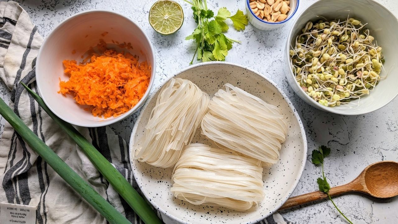 rice noodles, carrots, bean sprouts, green onions, cilantro all in bowls on a white background