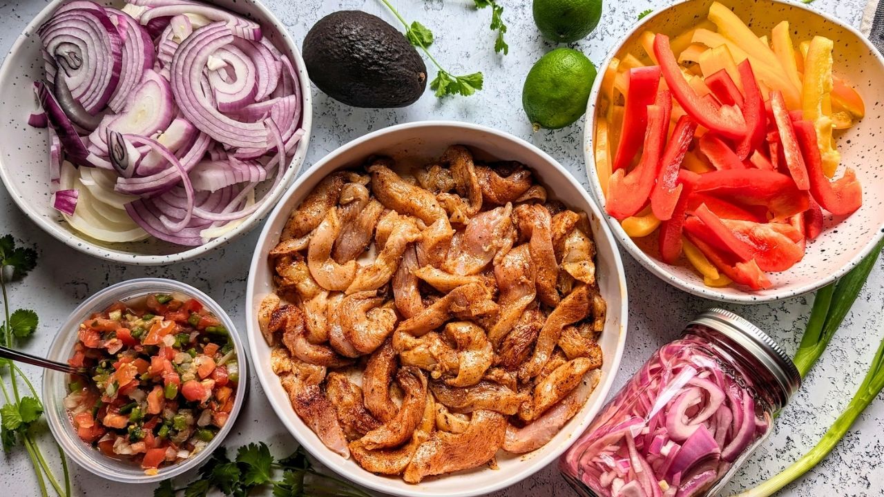 marinated chicken fajitas with sliced onions, bell peppers, pickled onions, salsa, avocado, and lime