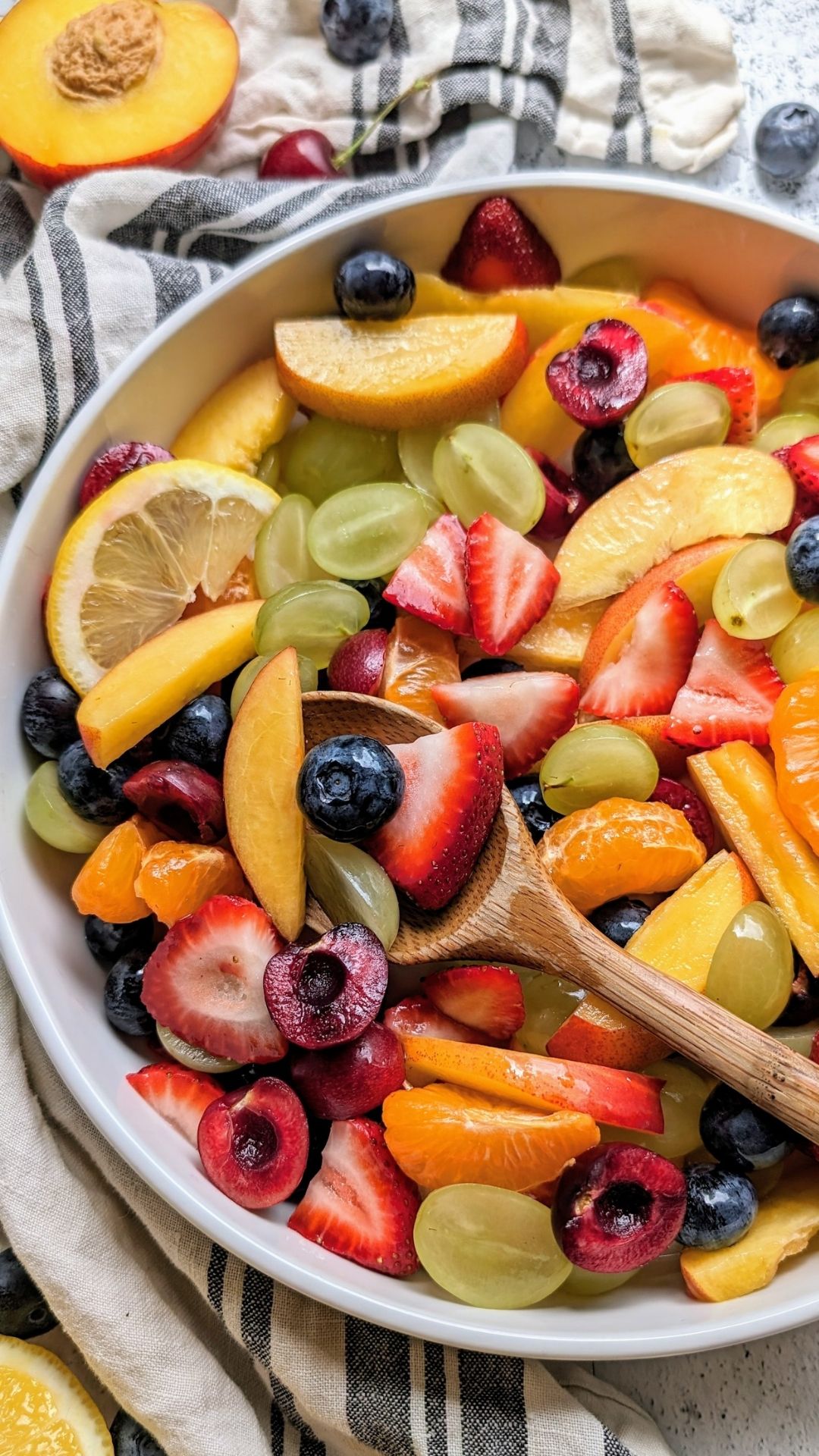 a big bowl of colorful fruit salad with fresh chopped fruit and a spoon