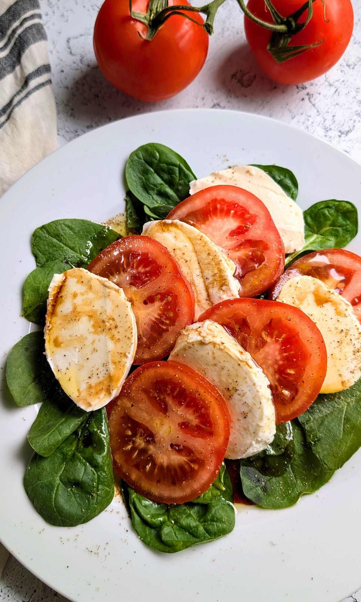 a plate with a tasty low sodium summer salad of sliced tomato with basil and low salt mozzarella cheese packed in water.