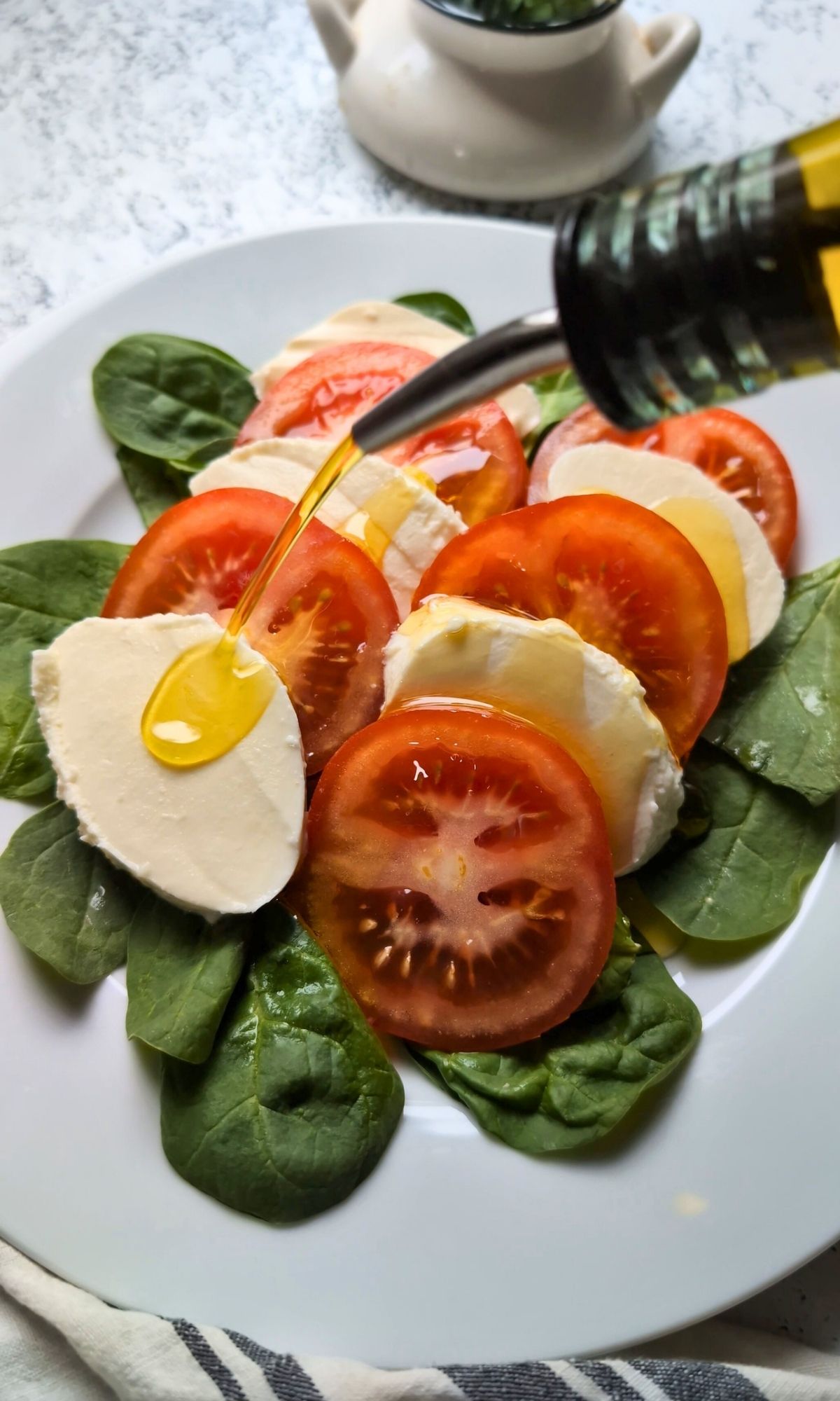 extra virgin olive oil drizled over a caprese salad with fresh mozzarella and vine ripe tomatoes.