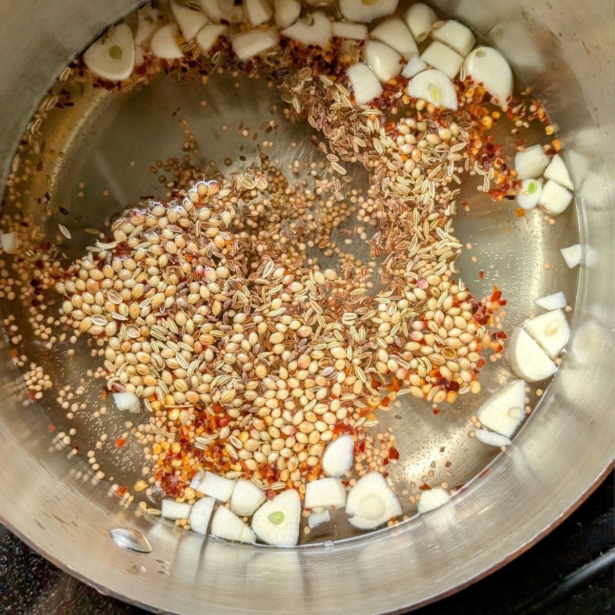 a pan of pickle brine without salt and with garlic mustard seeds dill seed and fennel.