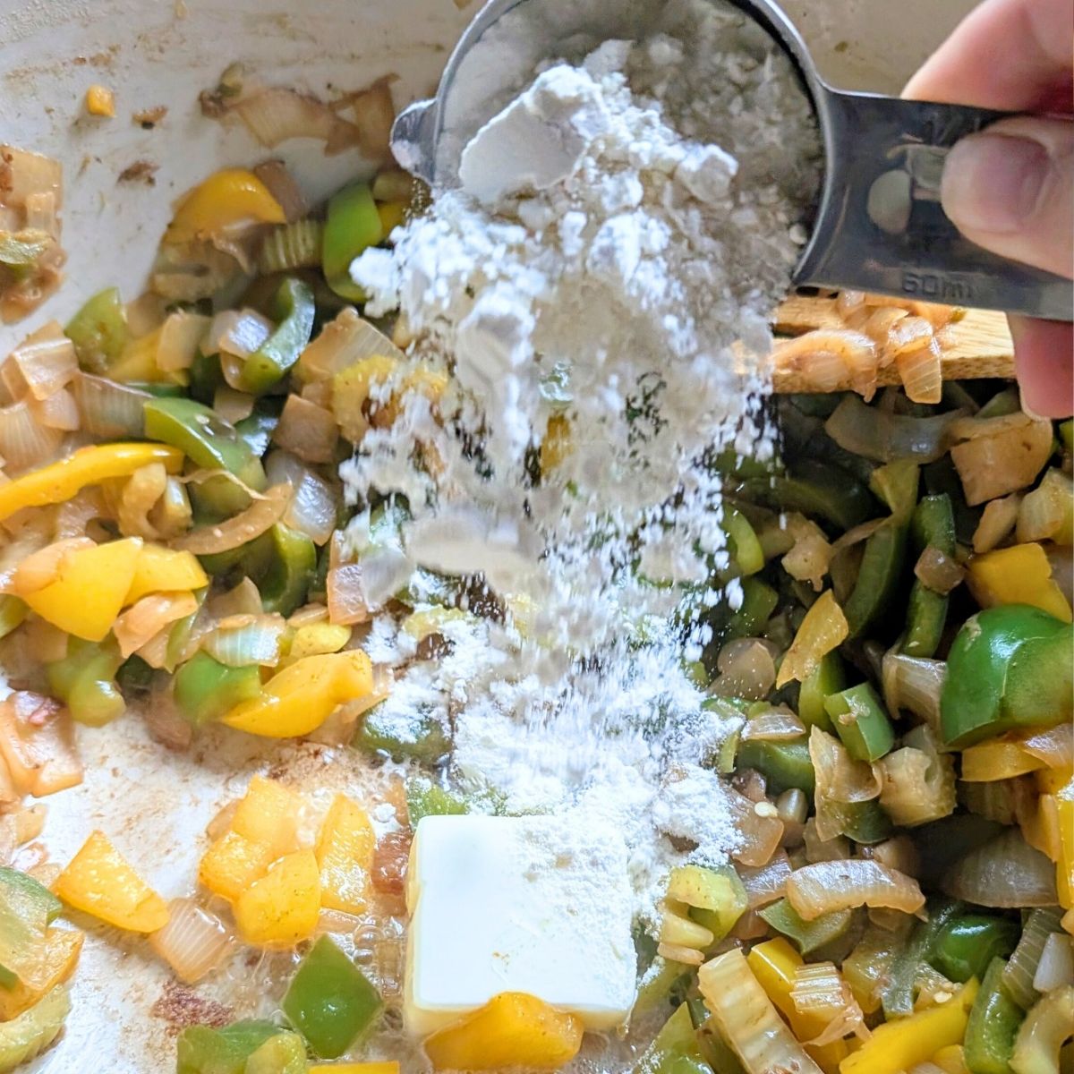 butter and flour being added to a pot of jambalaya to make a creamy roux for a new orleans style jambalaya with no salt.