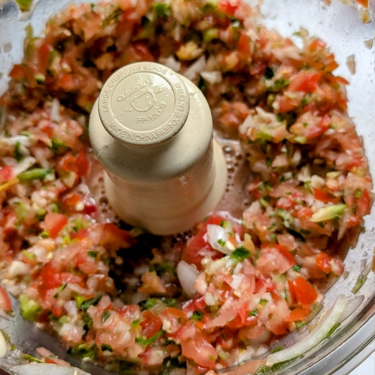 a food processor filled with finely chopped salt free salsa in a pico de gallo mexican style salsa fresca.