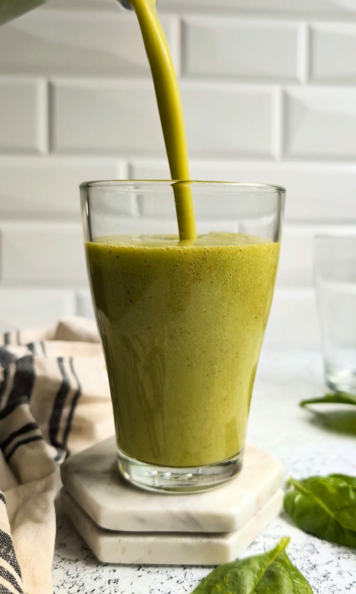 a green smoothie being poured into a glass ready for a healthy breakfast idea