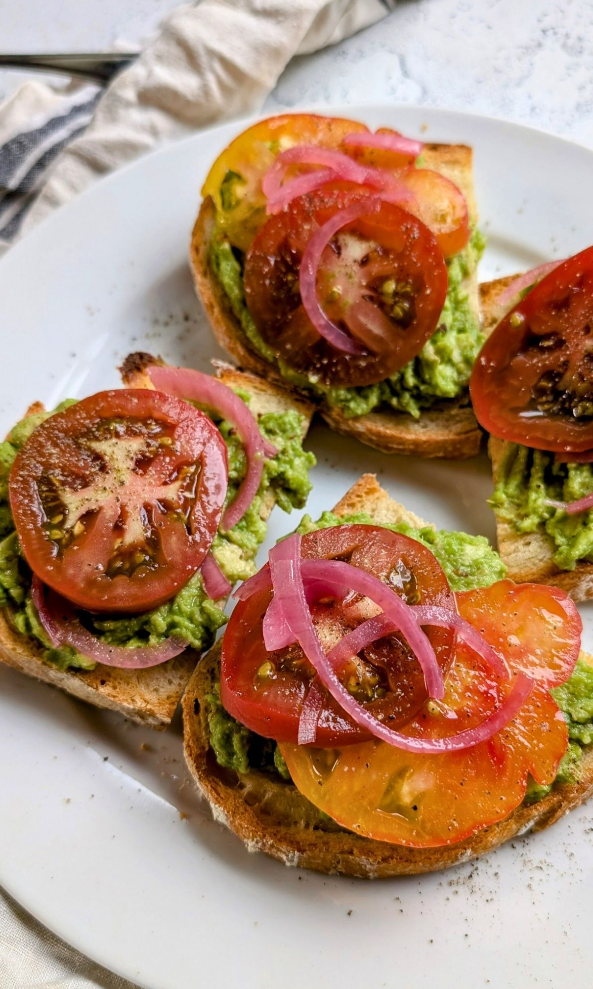 a plate of low sodium toast with avocadoes, tomatoes, and pickled onions without salt.