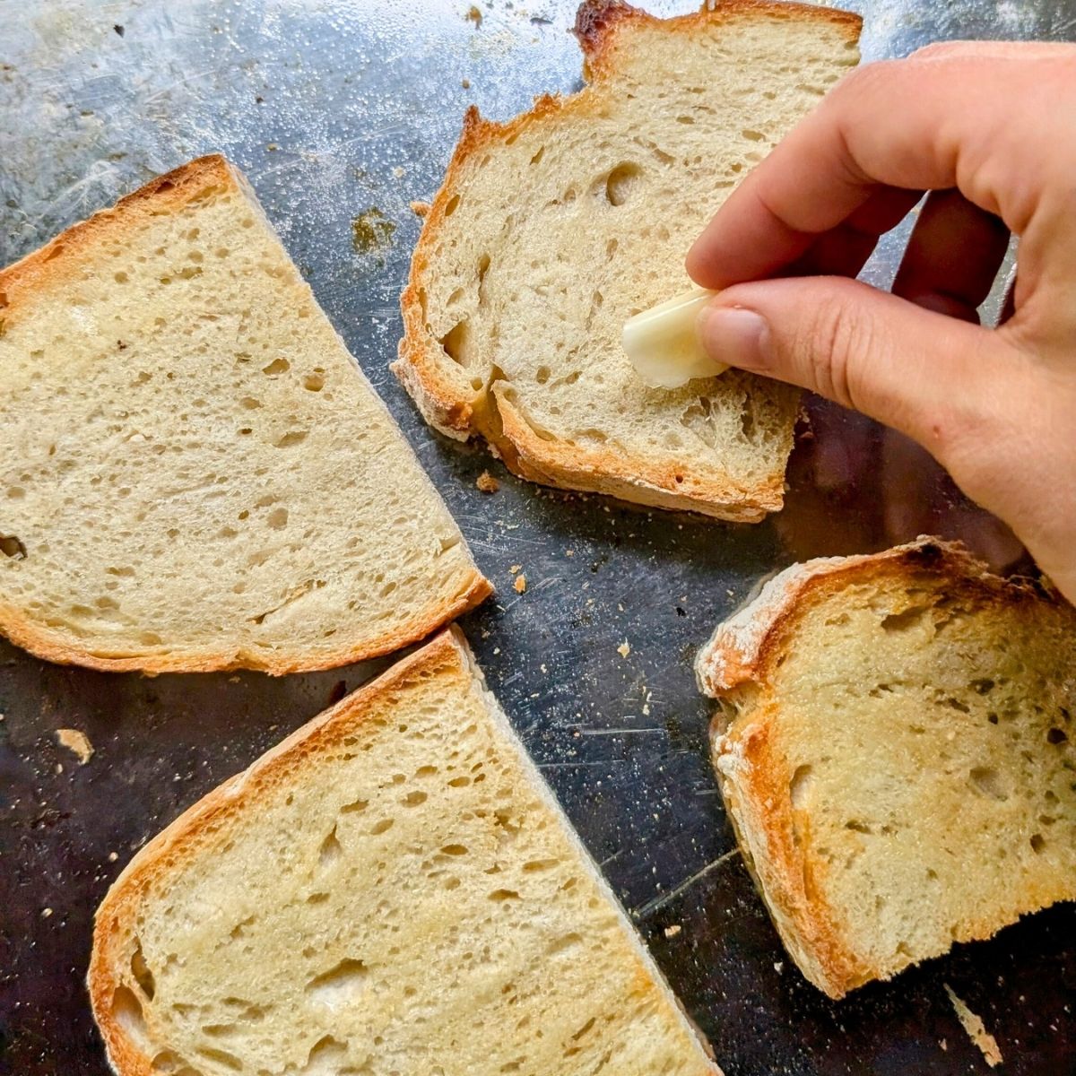 toasted bread being rubbed with fresh garlic to make low salt avocado toast.