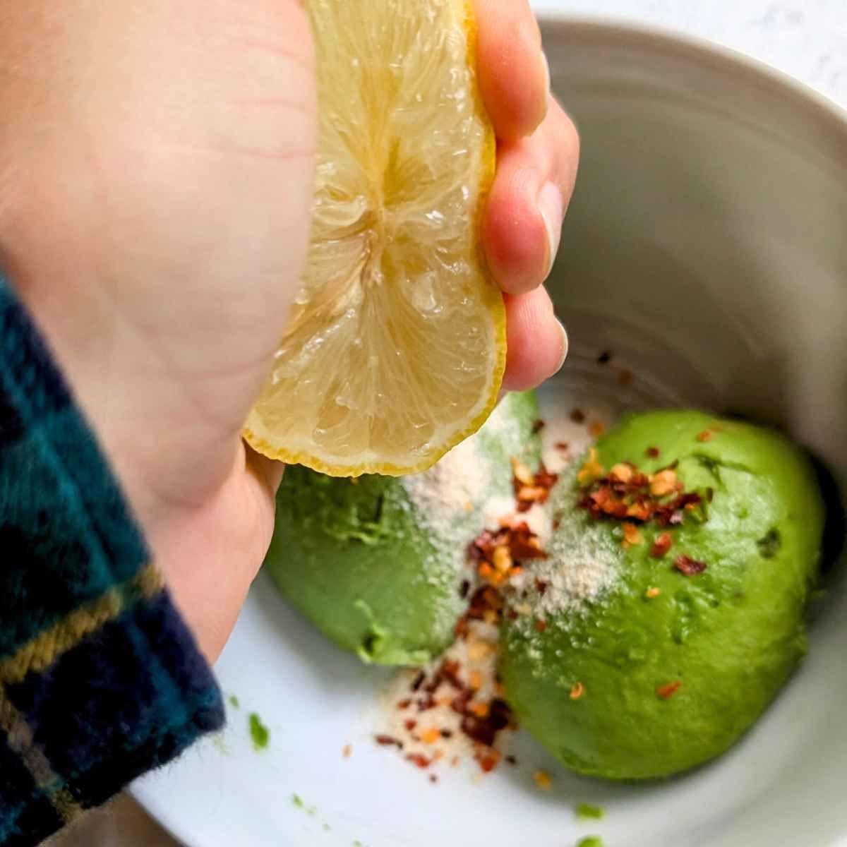 a bowl with avocado, chili flakes, onion powder, and fresh lemon.