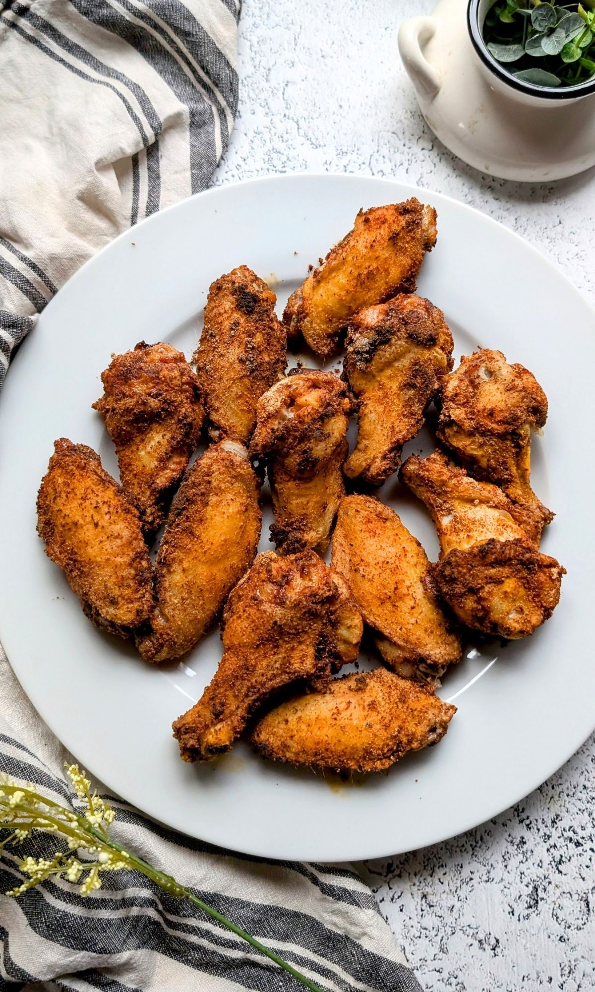 low sodium crispy chicken wings on a plate with a napkin and greens on the counter.