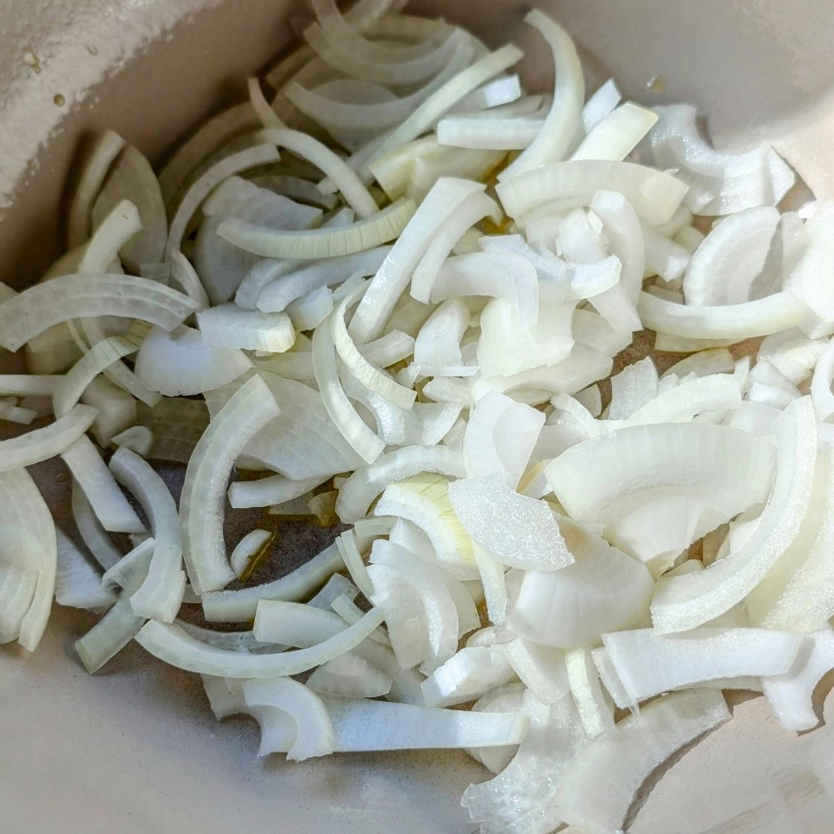 thinly sliced sweet onions in a pot getting ready to be made into onion dip and slow caramelized.