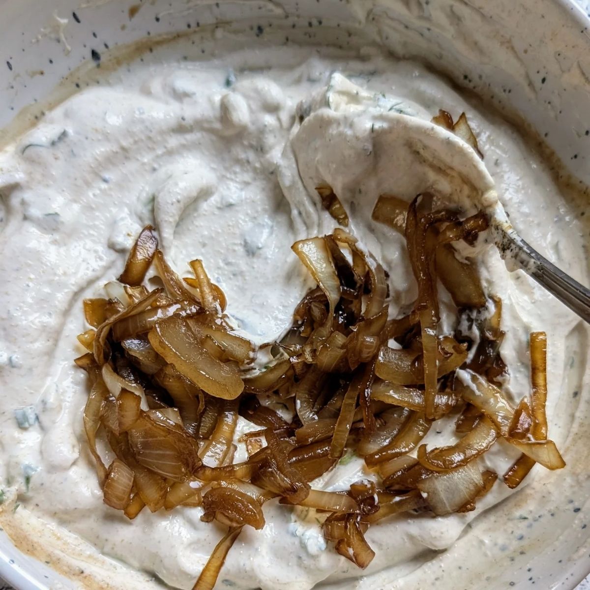 caramelized onion dip that is low in sodium being stirred with a spoon to make a creamy low salt snack dip.