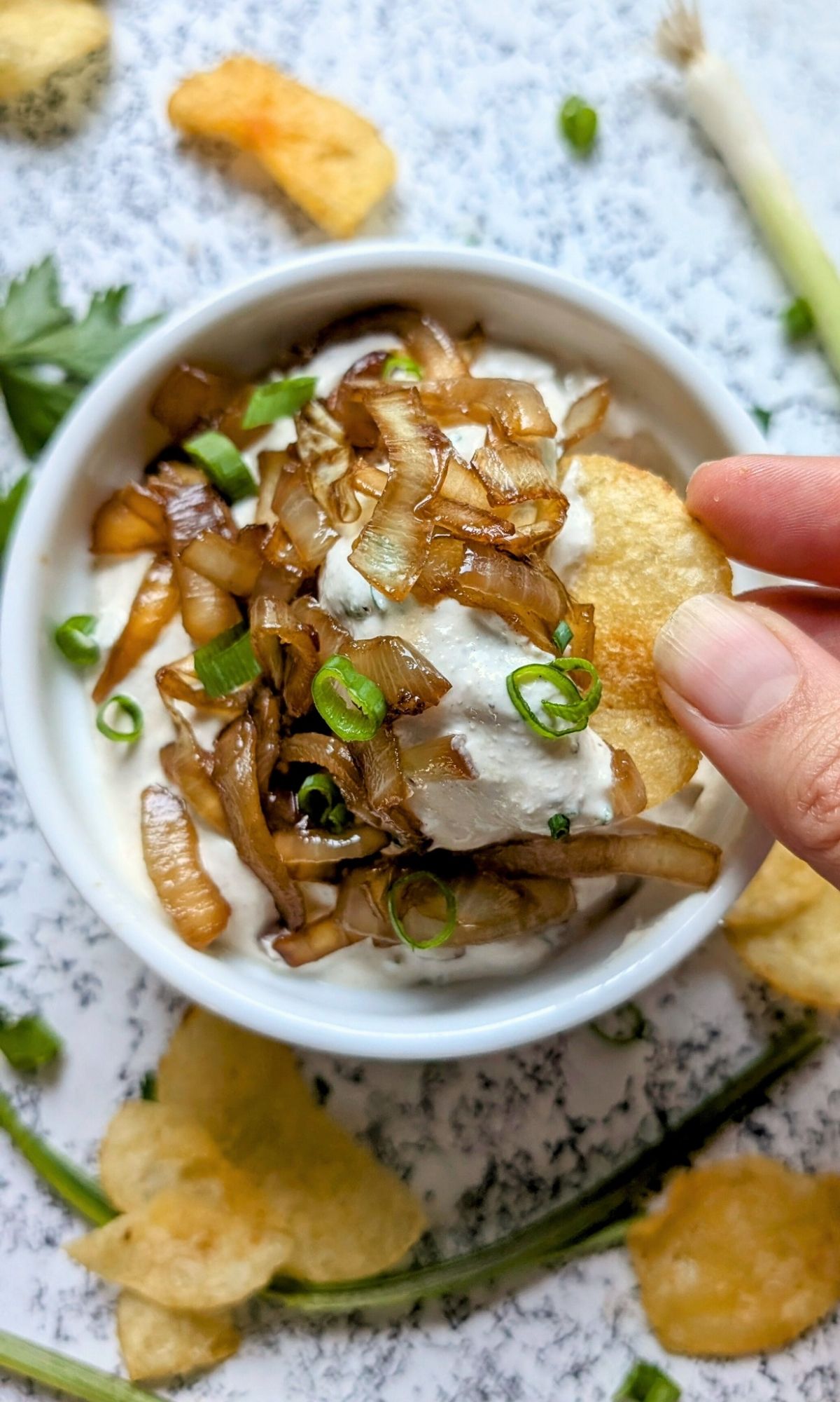 low salt sour cream and caramelized onion dip for chips, being dipped by am unsalted kettle potato chip.