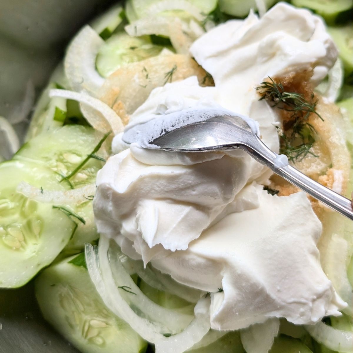 a spoon mixing in low sodium sour cream into this tasty side salad.