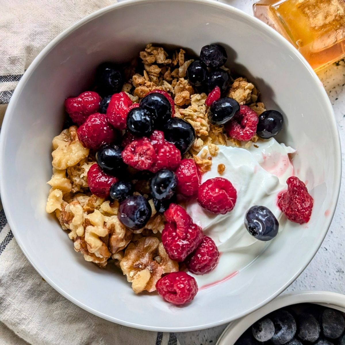 a healthy yogurt bowl recipe with no salt added granola, fruit, and nuts in a bowl.