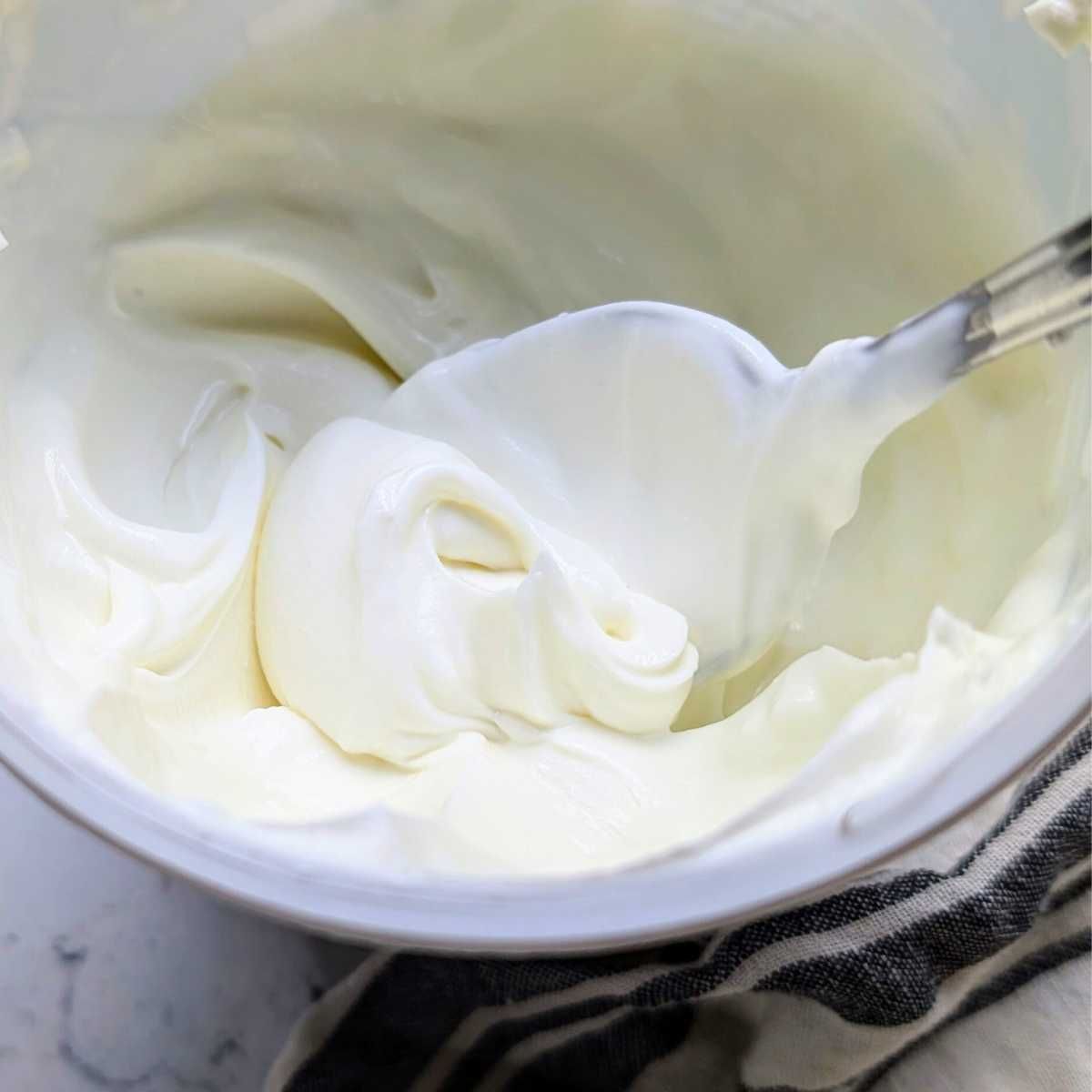 plain unsweetened greek yogurt being stirred by a spoon for a low sodium breakfast.