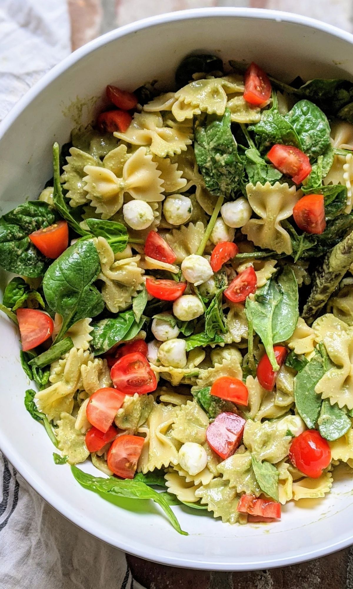 a bowl of low sodium caprese pasta salad with fresh mozzarella cheese cherry tomatoes and basil vinaigrette.