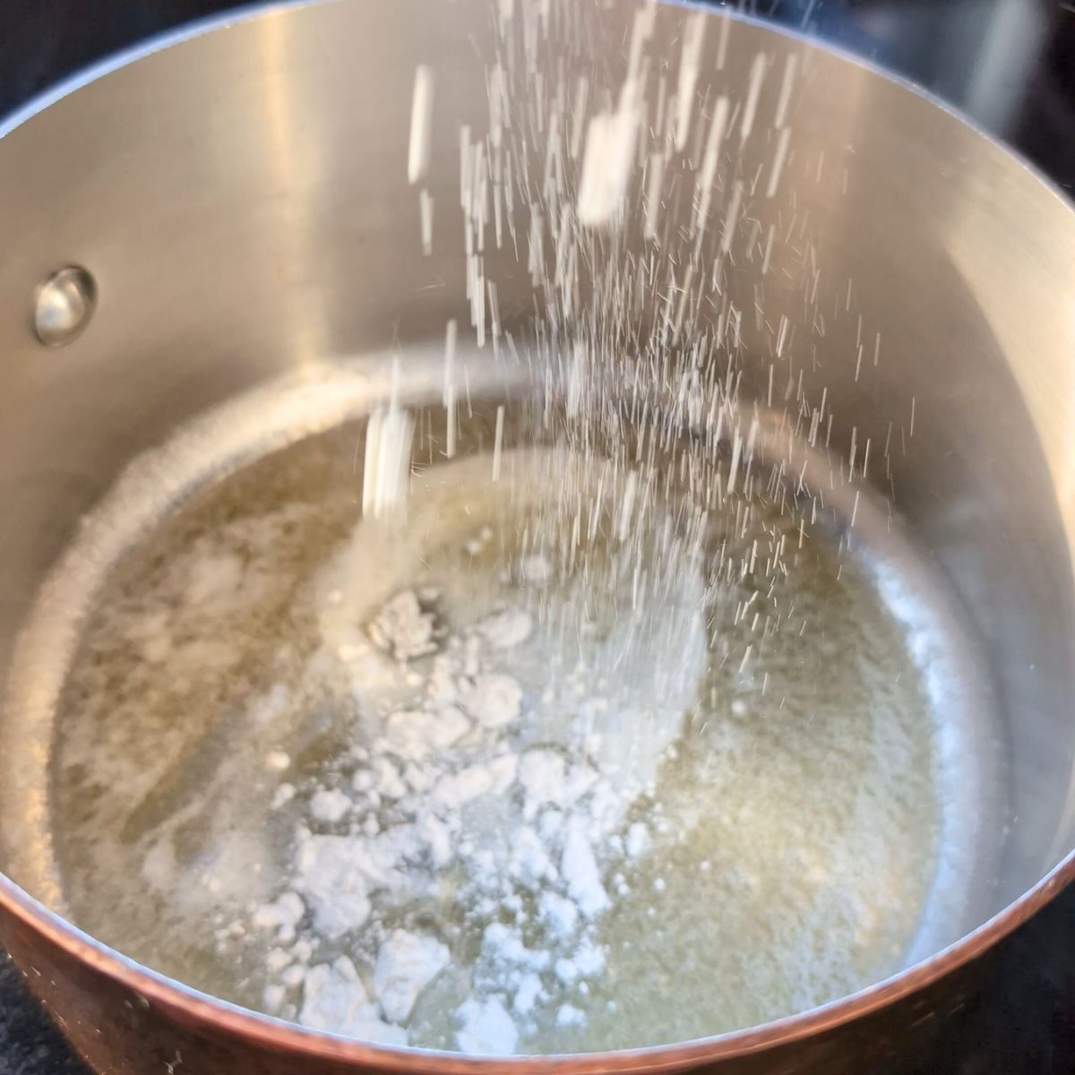 a saucepan with melted butter and all purpose flour sprinkled in to make a roux.