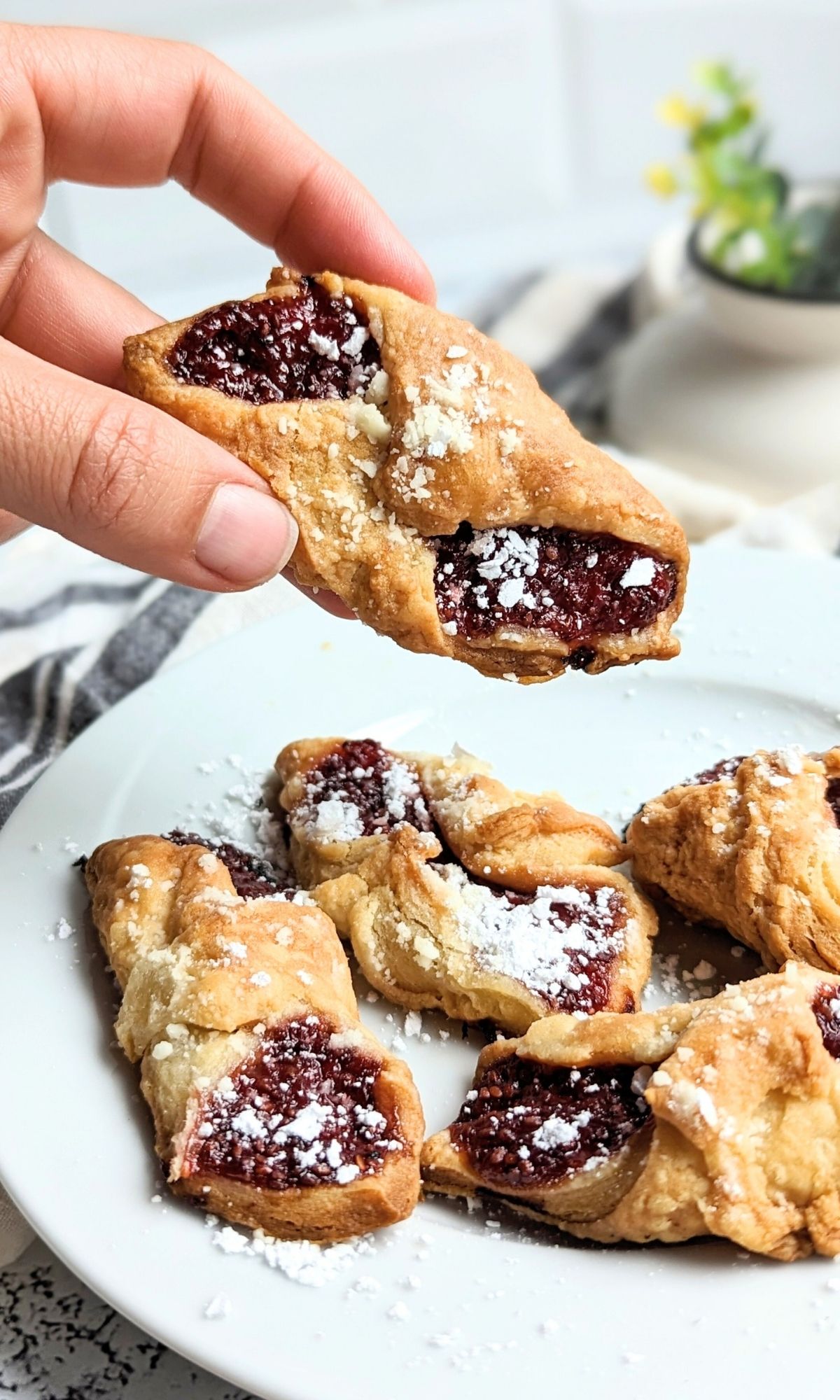 a hand holding a low sodium jam cookie with cream cheese and unsalted butter cookie dough and jelly filling