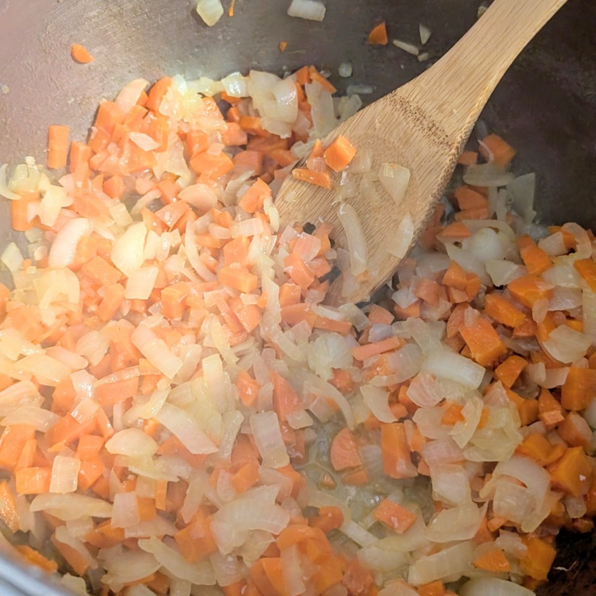 a pot with carrots and onions and garlic sautéing to no salt added chicken and dumplings