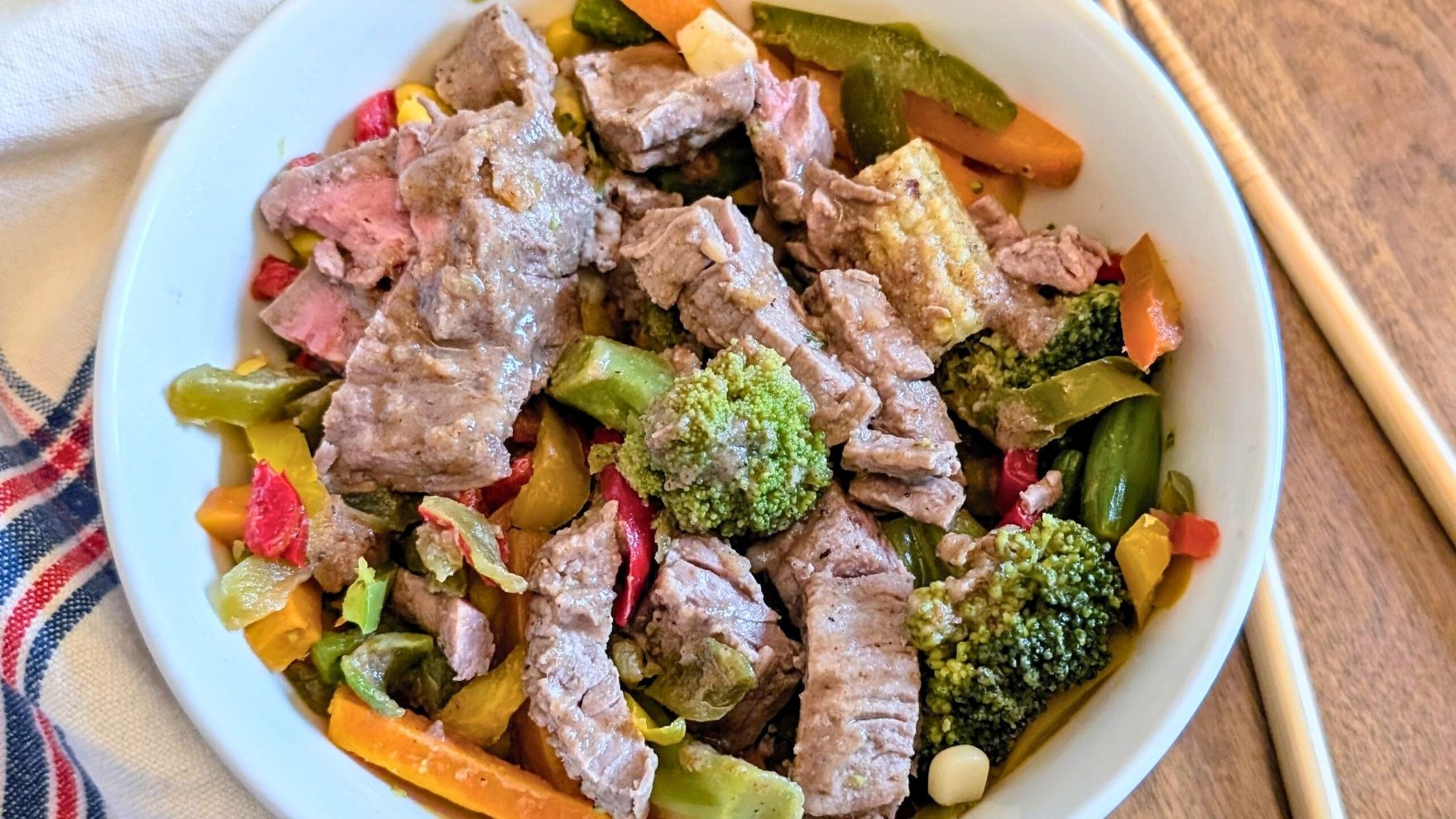 a bowl of low salt stir fried beef and broccoli with vegetables and carrots.