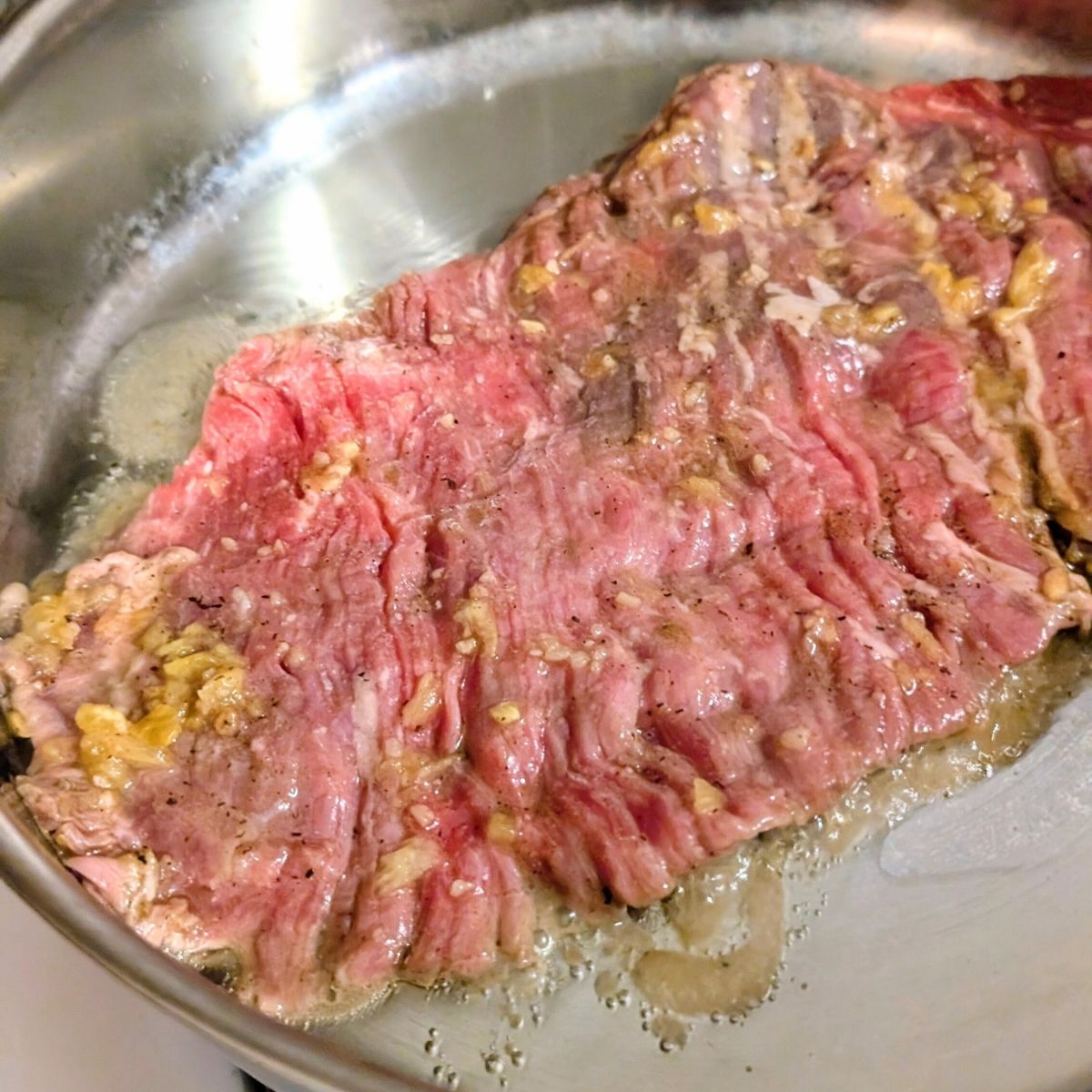 a pan of low sodium skirt steak with pineapple and cumin being seared