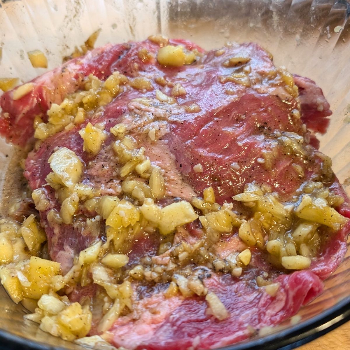 a bowl of skirt steak with chopped pineapple and garlic marinade in a bowl