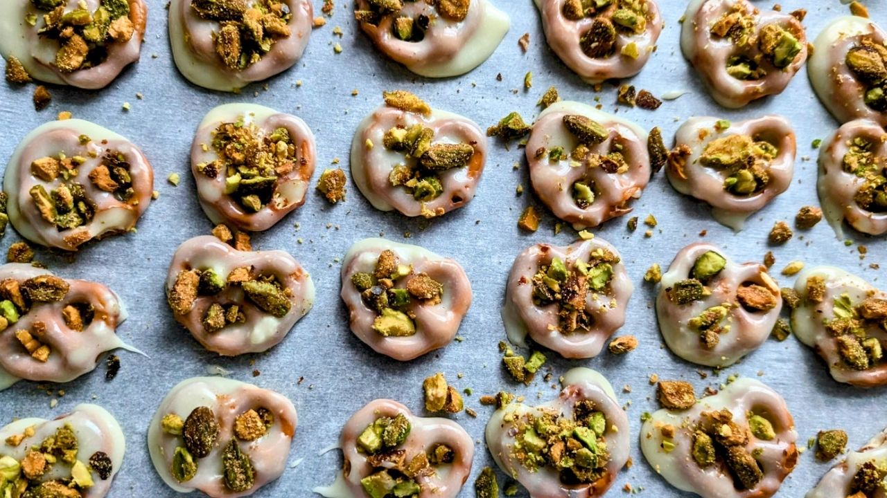 a tray of unsalted pretzels dipped in white chocolate and covered in crushed nuts with cinnamon sugar.