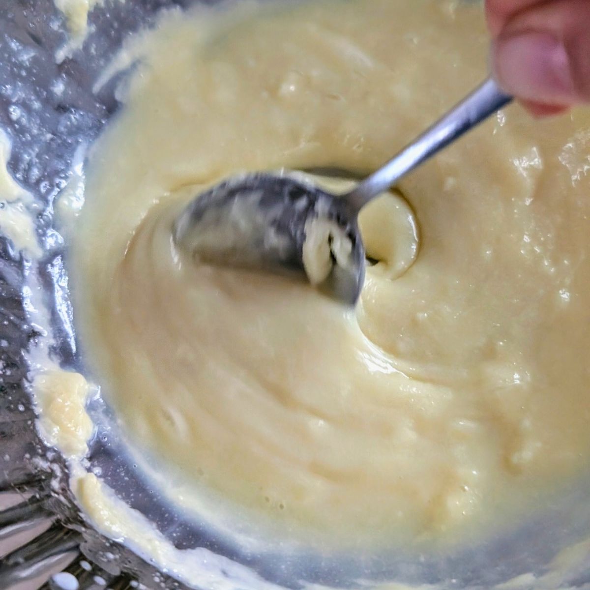 melted white chocolate in the microwave being stirred with a spoon until melted.