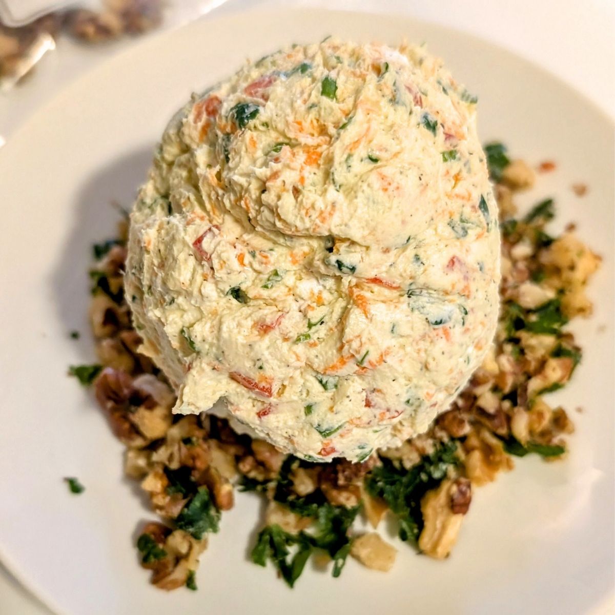 a salt free cheese ball being rolled in crushed walnuts and parsley