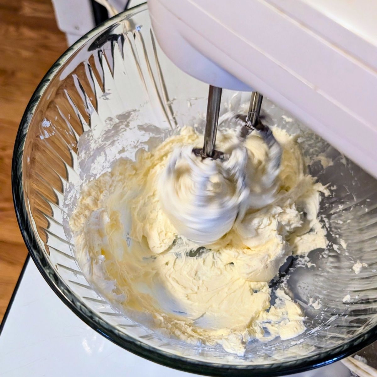 cream cheese being mixed by a hand mixer