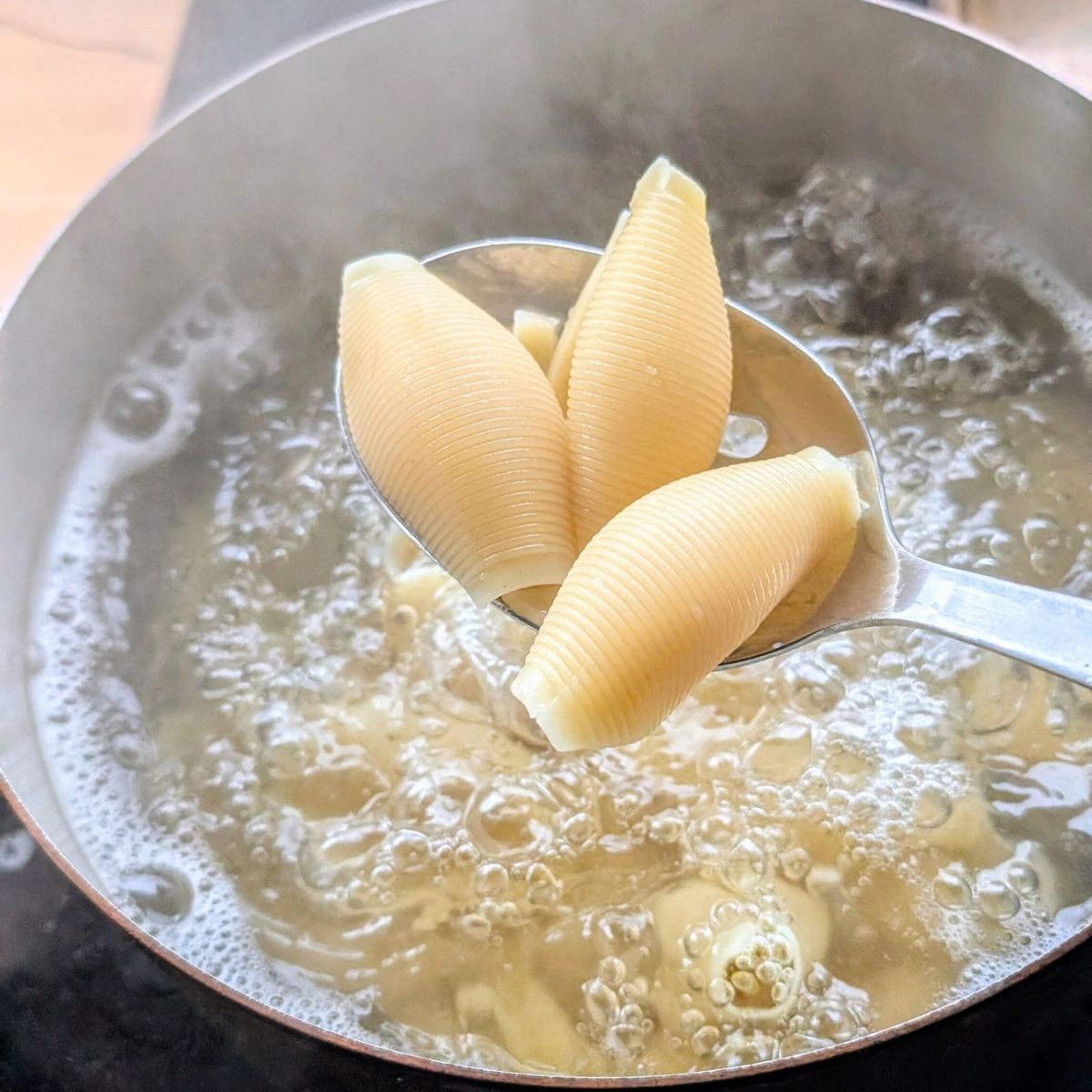 cooked jumbo shells in a pot of boiling water