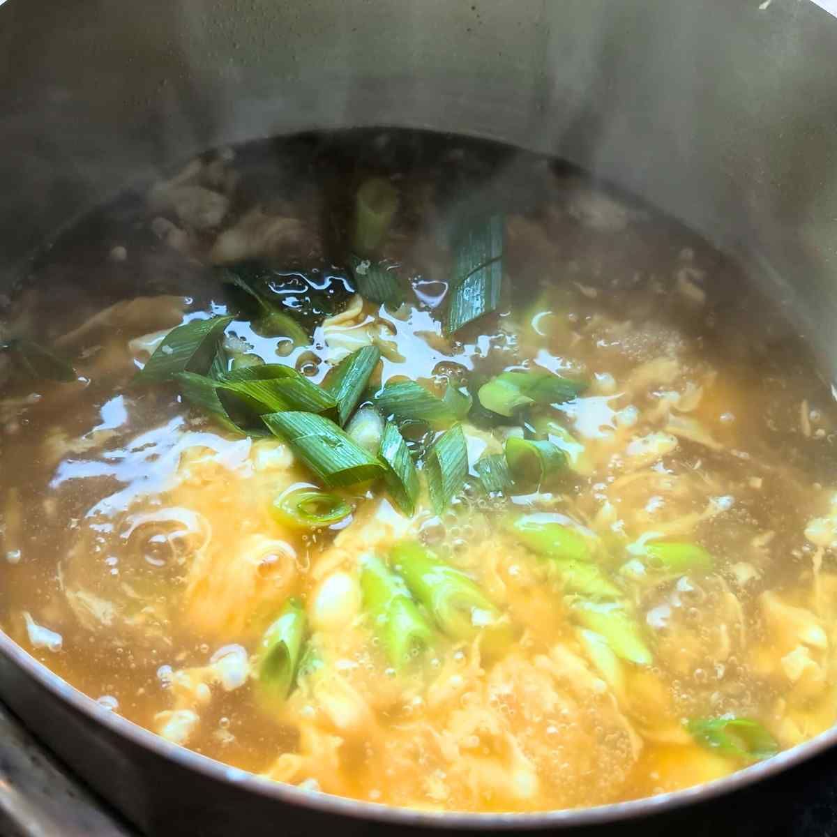 a pot with scallions and a yellow egg drop soup low in sodium 