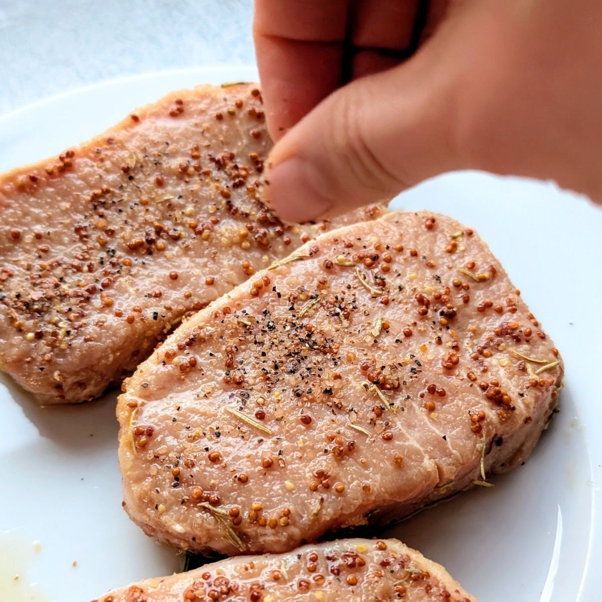 pork being seasoned with no-salt-added steak spice