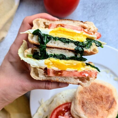 low sodium breakfast sandwiches sliced in half showing the inside of eggs, spinach, and tomatoes