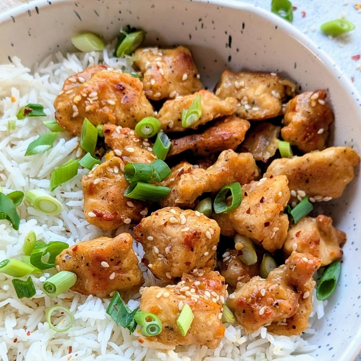 crispy low sodium orange chinese chicken recipe with green onions and white rice.