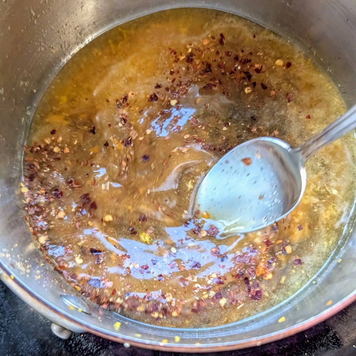 low sodium orange chicken sauce on a stove made with orange juice, brown sugar, rice vinegar, and chili flakes.