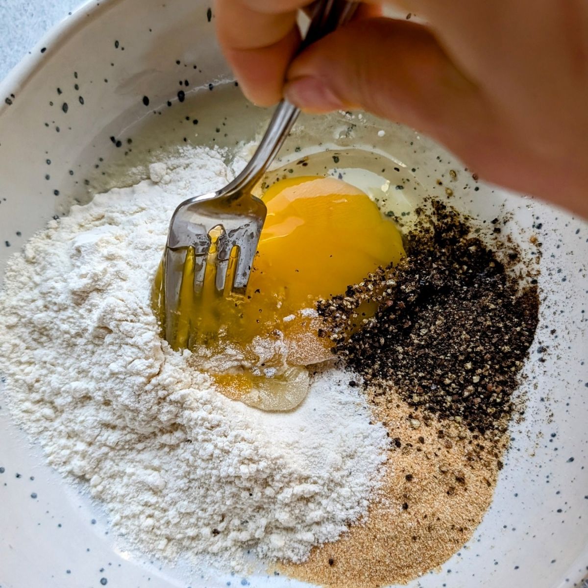 a bowl with low sodium batter for orange chicken made with flour, egg, pepper, and garlic powder.