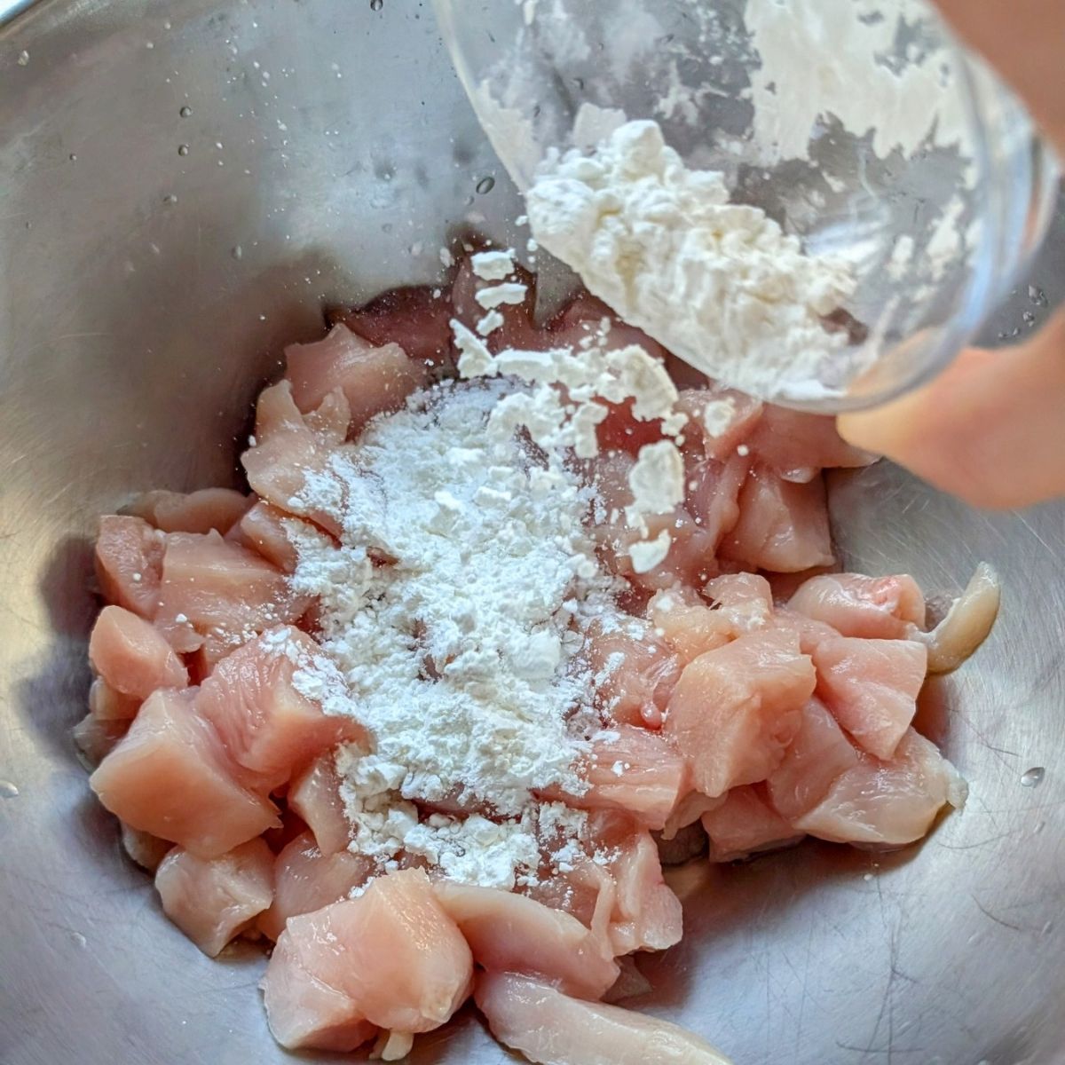 uncooked chicken in a bowl with corn starch to make a crispy orange chicken dinner low in sodium