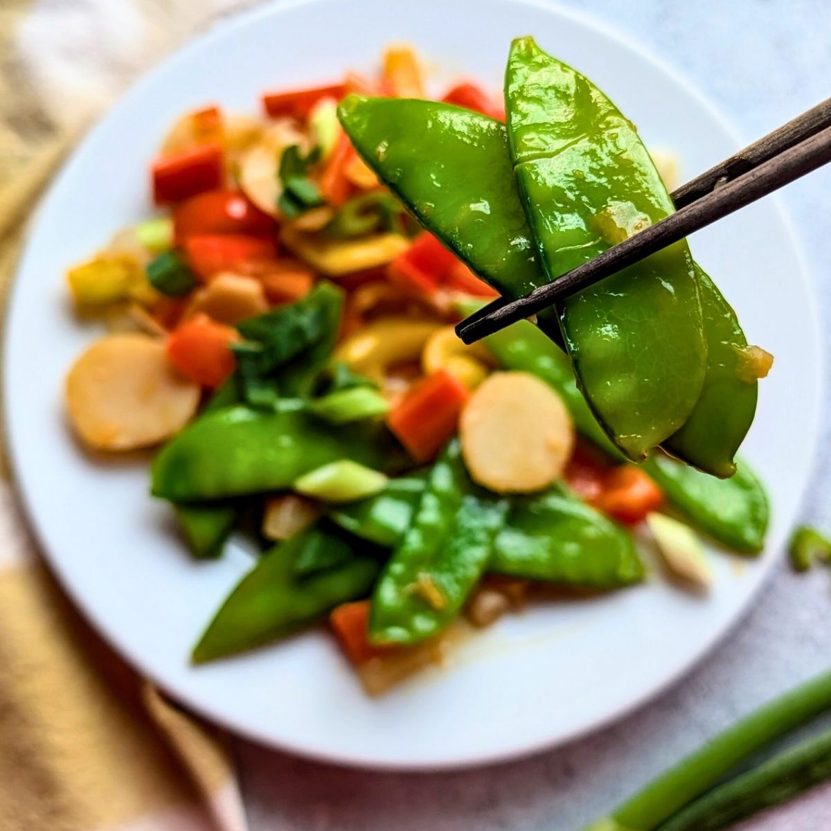 chopsticks with low sodium pea pods and asian vegetables on a plate for stir fry