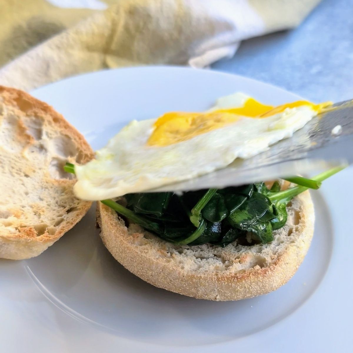 a toasted engilsh muffin with sauteed spinach and a fried egg without salt