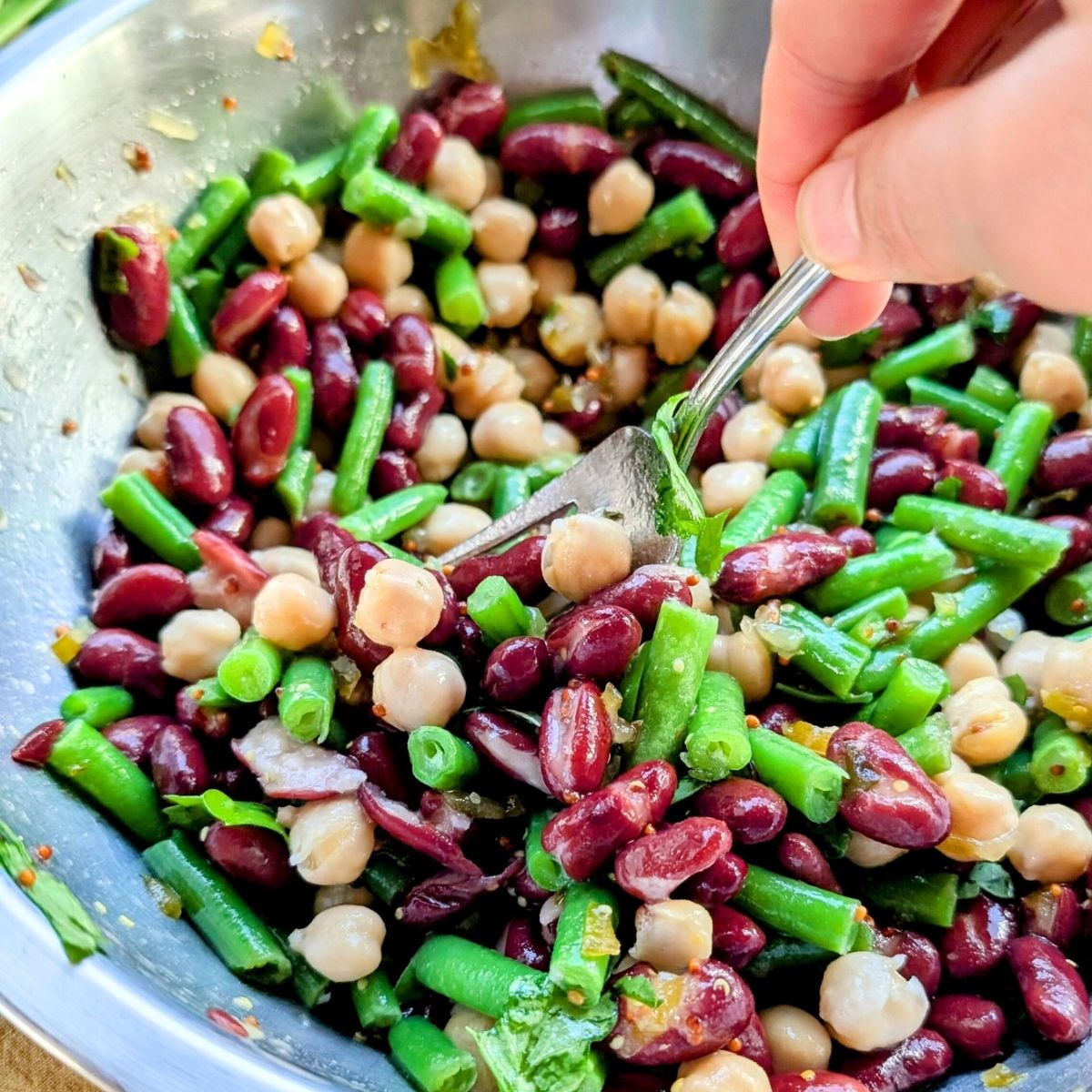 a fork mixing low sodium 3 bean salad with dressing and no salt added