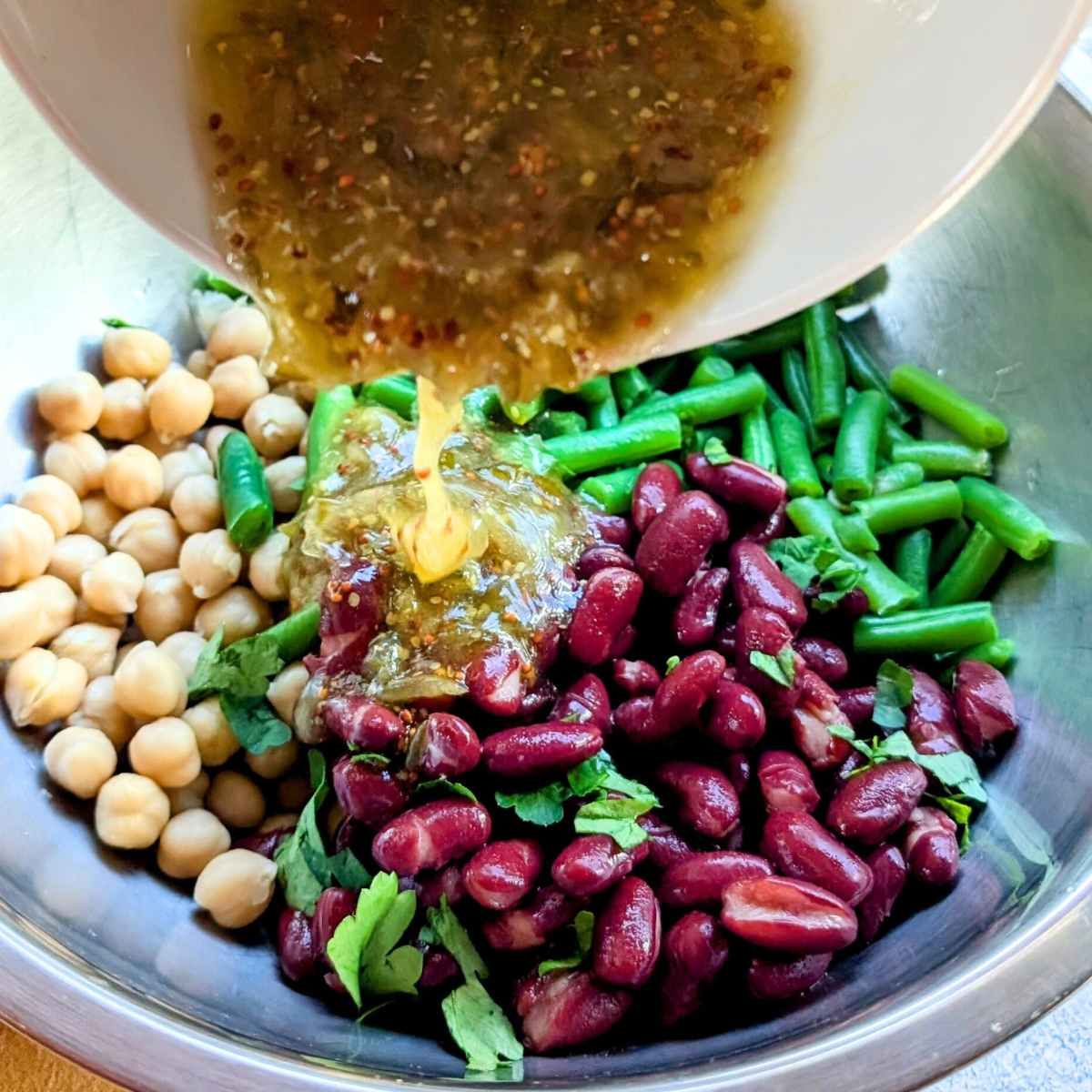 low salt three bean salad recipe with dressing being poured over the top.