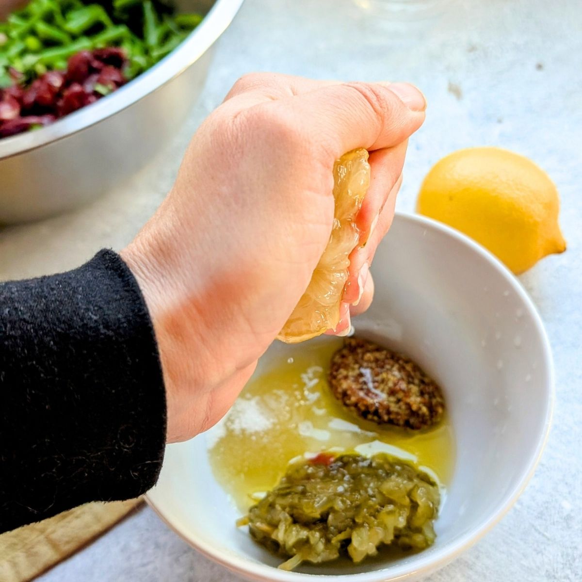 a mixing bowl with relish olive oil vinegar sugar and fresh lemon juice.